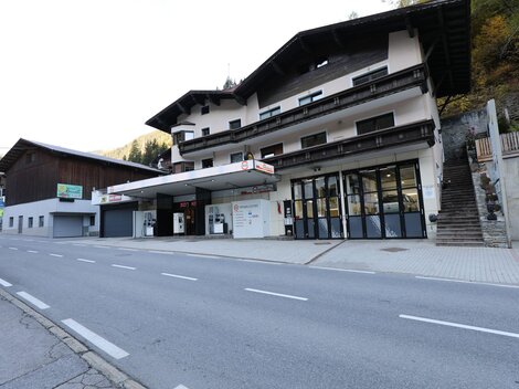 Eine ruhige Straße mit einem großen, traditionellen Gebäude. Das Gebäude scheint Geschäfte und Dienstleistungen anzubieten.