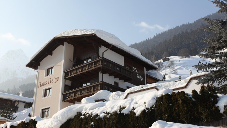 A cozy house in the mountains, surrounded by snow and fir trees. The snow-covered landscape radiates tranquility and beauty.
