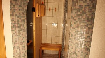 A beautiful sauna area with a decorative arch made of tiles. Inside, there is a wooden bench and a corner for relaxation.