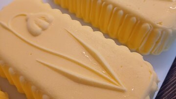 Zwei gelbe Butterstücke mit floralen Mustern. Die Oberfläche ist glatt und glänzend.