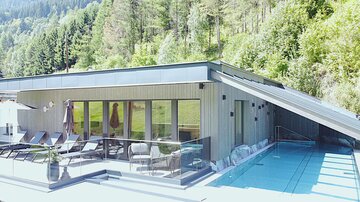 A modern house with a large terrace and a pool.  
Surrounded by green trees and a beautiful landscape.