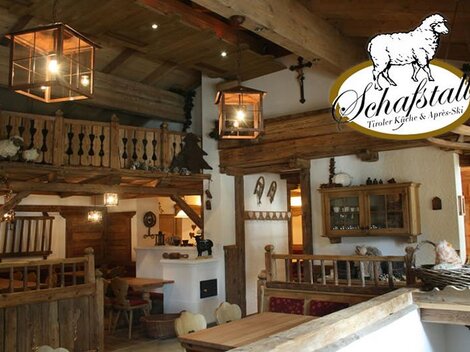 A cozy restaurant with rustic wooden interiors and warm lighting. In the background, tables and a comfortable atmosphere can be seen.