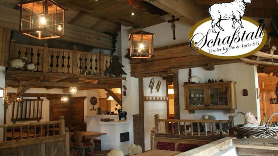 A cozy restaurant with rustic wooden interiors and warm lighting. In the background, tables and a comfortable atmosphere can be seen.