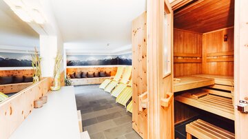 A modern sauna area with wooden paneling and comfortable loungers. The atmosphere is relaxed and inviting.