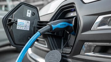 An electric car is charging with a charger. The plug is inserted into the vehicle's charging socket.